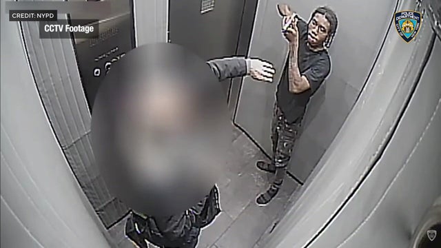 A man points a gun at another man in an elevator 