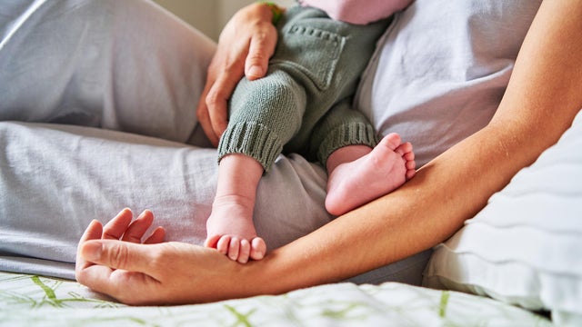 Baby eating from mother's breast while lying in bed 