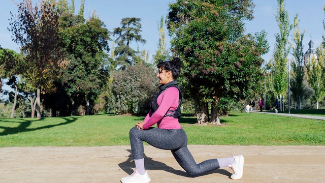 Young sportswoman stretching legs before running in a park 