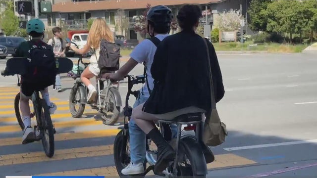 Teenagers crossing the street on their e-bikes 